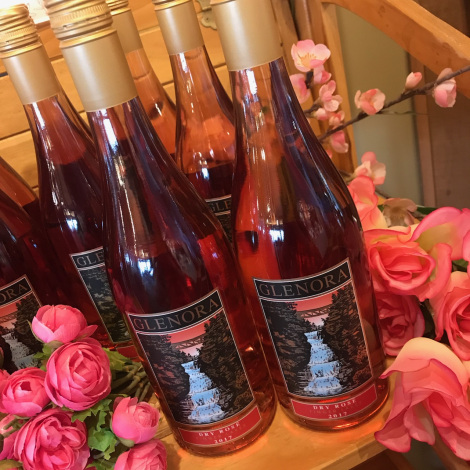 Bottles of Glenora's 2017 Rose, surrounded by pink roses